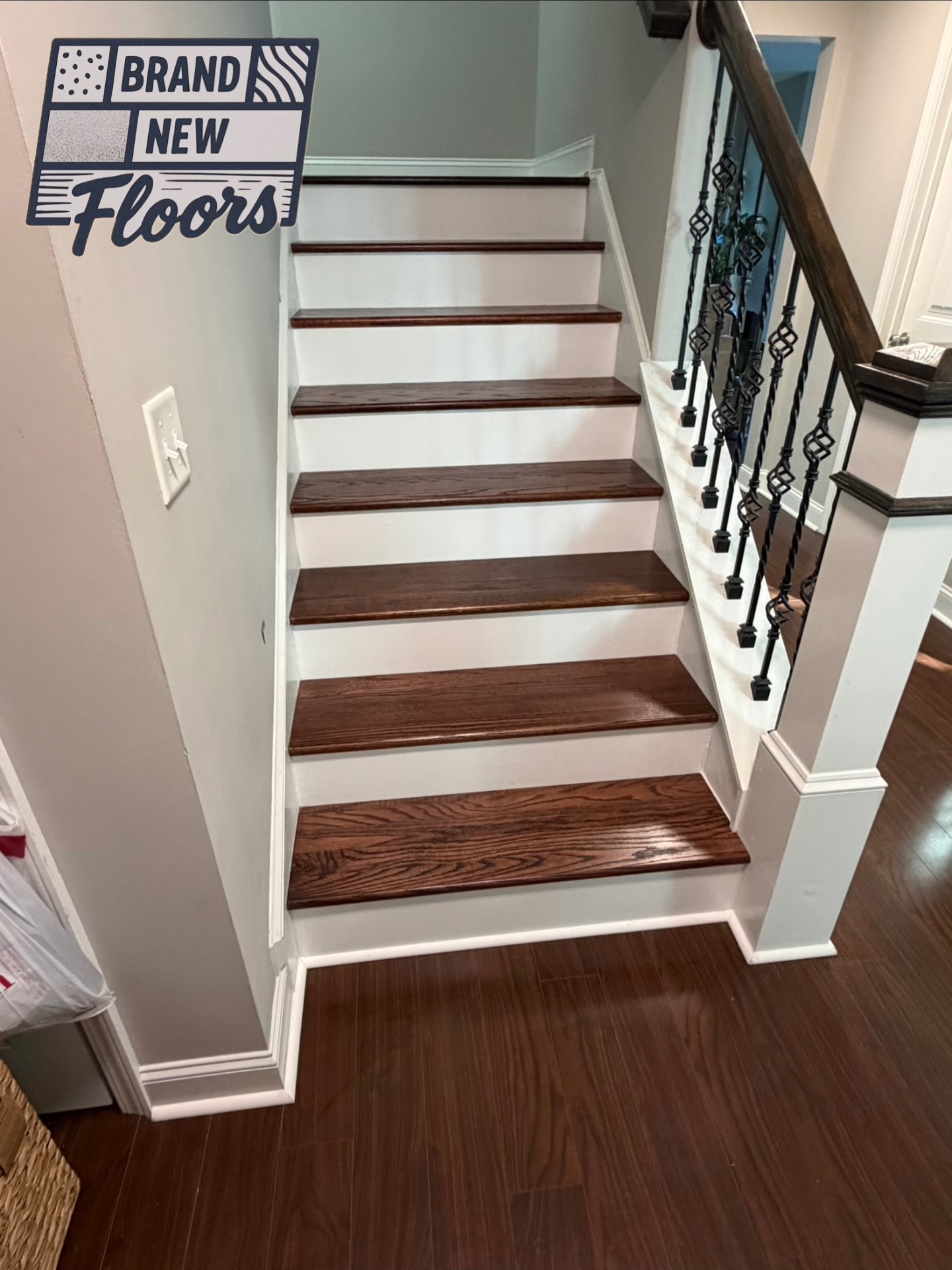 Dark wood staircase with white risers and iron balusters